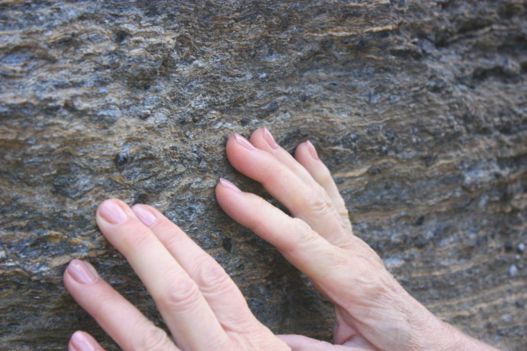 mani che toccano una roccia per capire la tessitura dei minerali presenti
